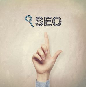 Hand pointing to SEO concept on light brown wall background